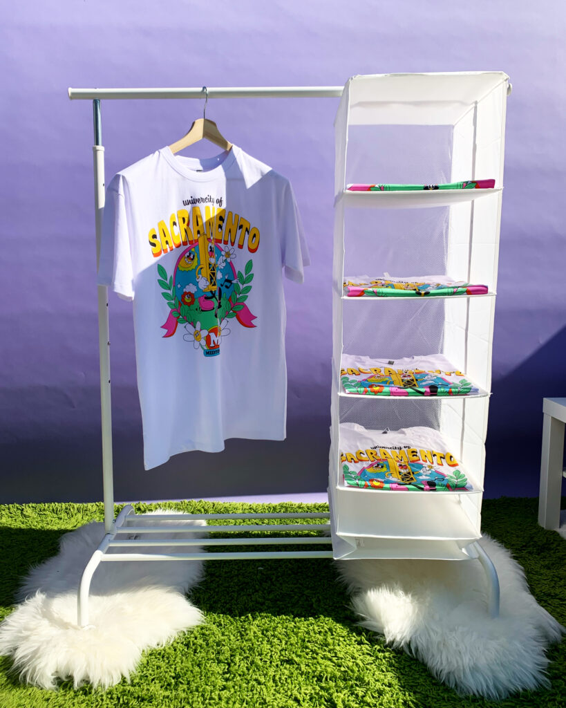 White Midtown t-shirt hanging on a white clothing rack with a purple wall background